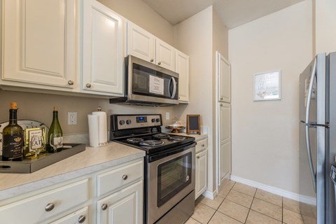 Model apartment kitchen with stainless steel appliances and white cabinets at Encore at Buckingham apartments in Richardson, TX